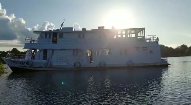 Traditional Amazon riverboat on the dark Rio Negro at sunset