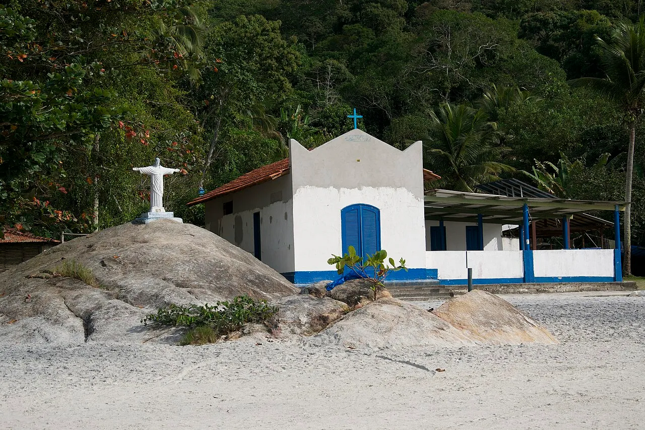 A small white chapel on the sand behind granite boulders at Aventureiro on Ilha Grande
