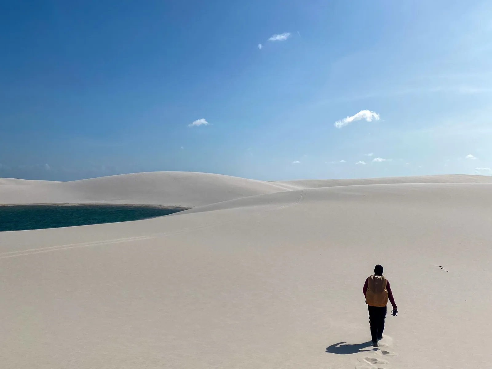A lone walker on a broad dune crest under a wide open sky