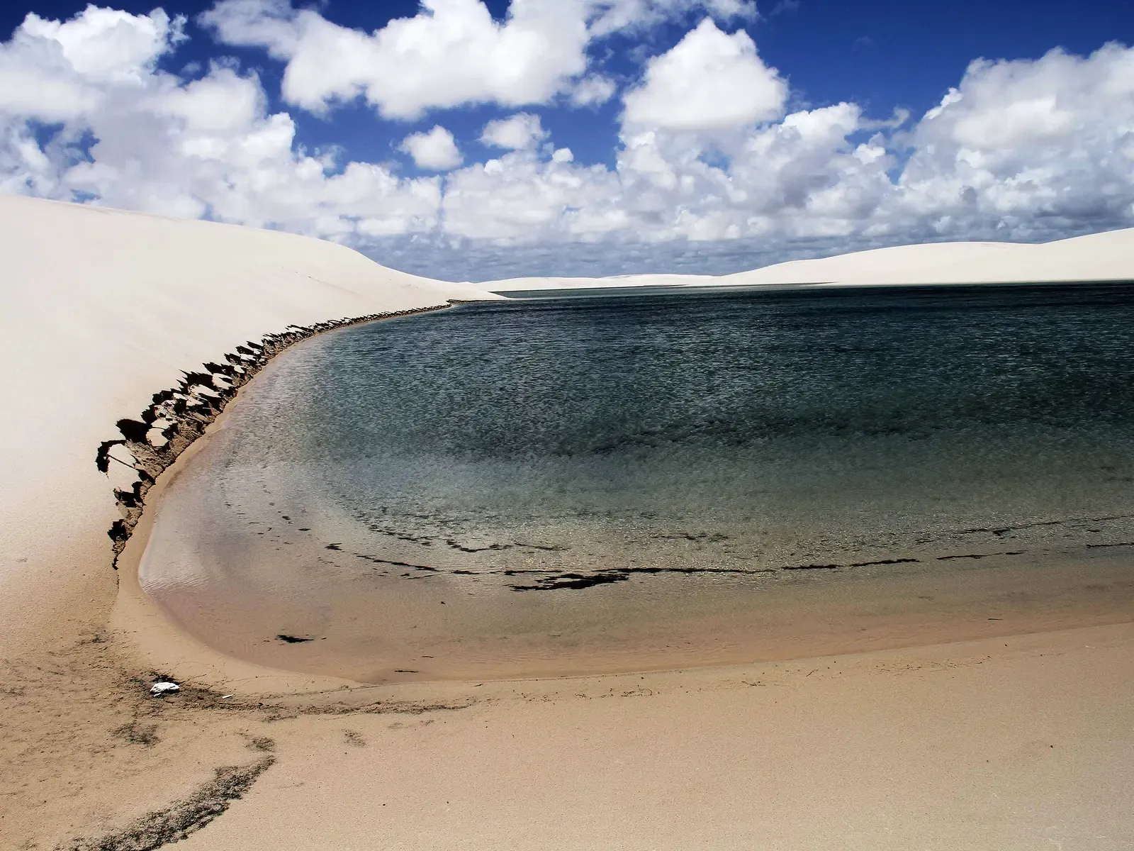 White dunes curving around the green water of Lagoa das Pedras, near Santo Amaro