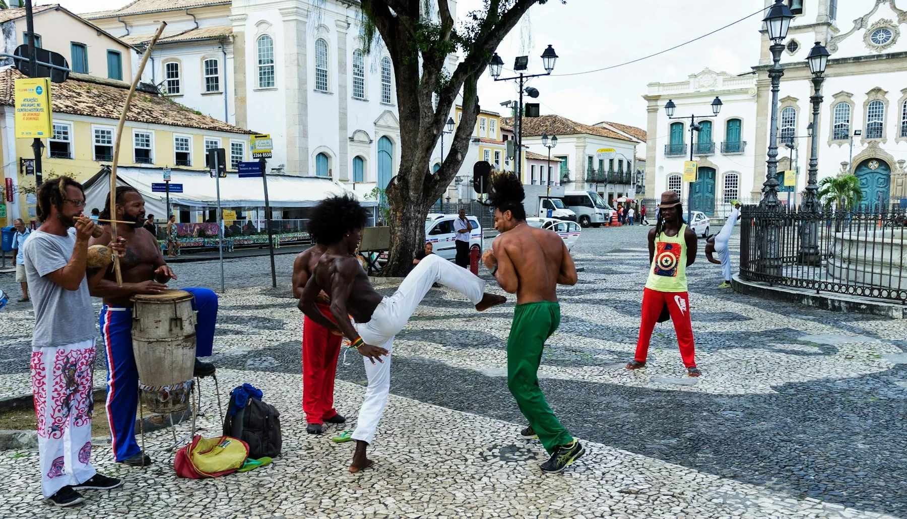 Capoeira players mid-move inside the circle, watched by the roda