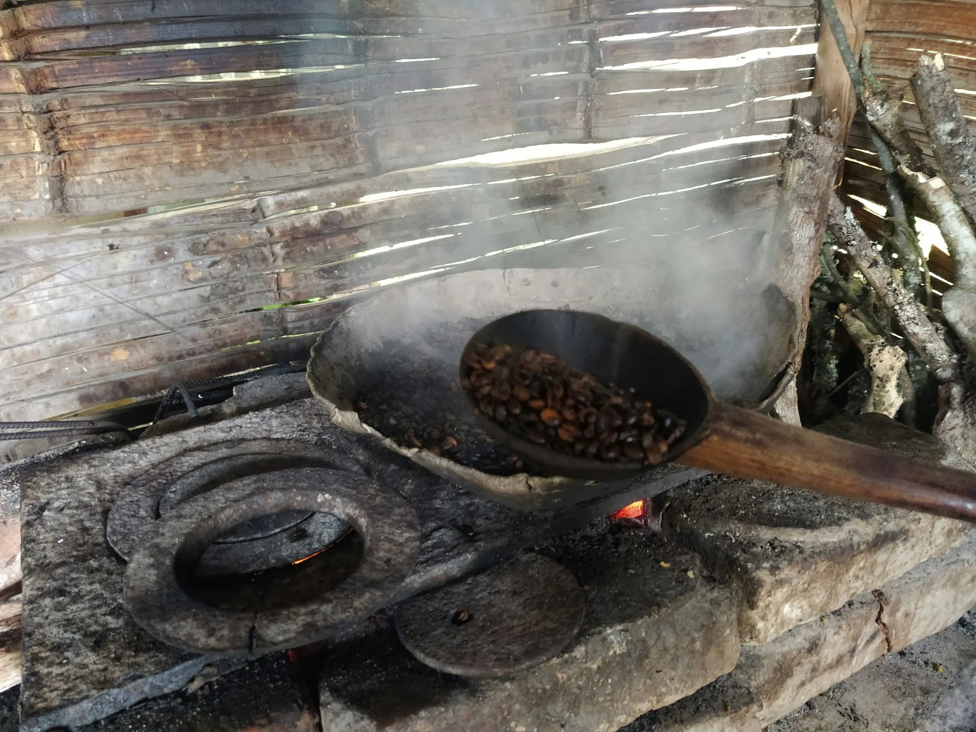 Cacao beans roasting in a pan over a wood fire