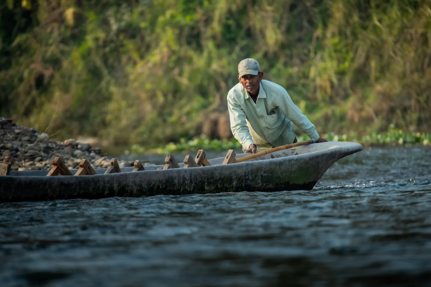 A fisherman paddling a traditional wooden canoe through calm water