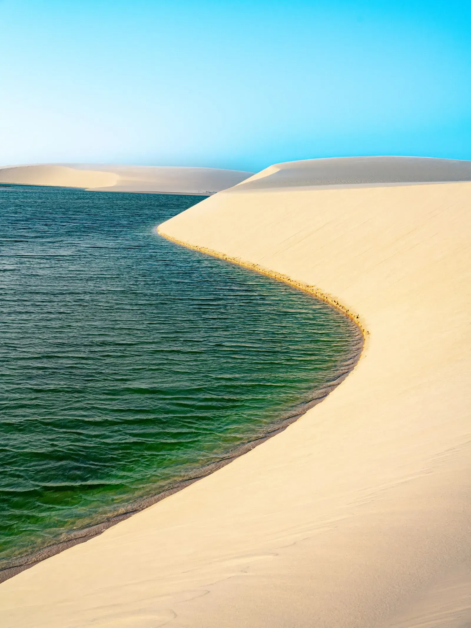 White sand dunes rippling to the horizon, cradling turquoise rainwater lagoons