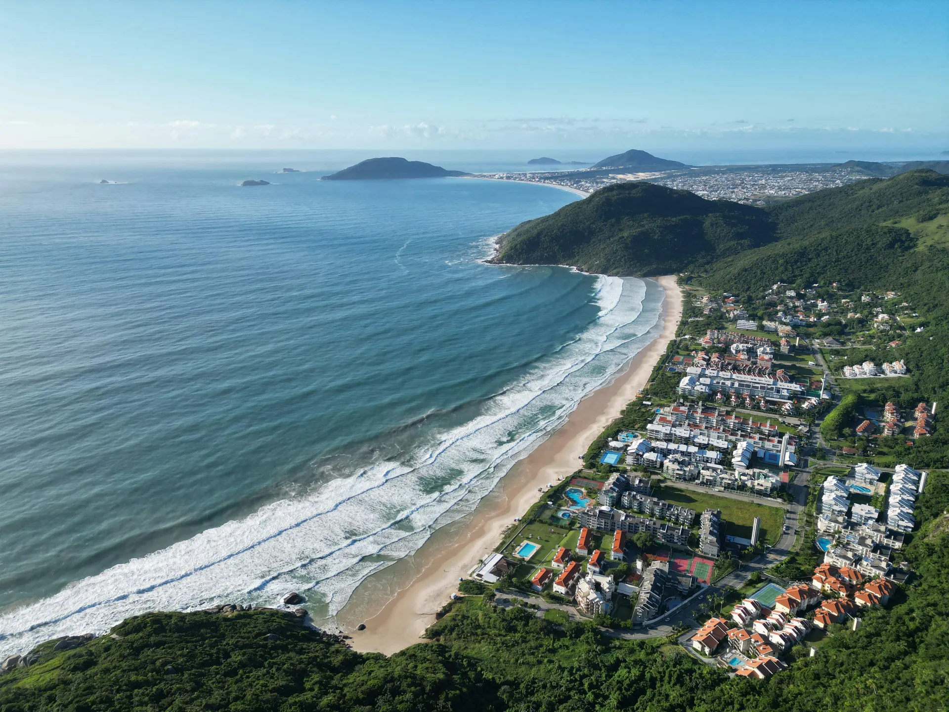 A bright, developed beach in the north with calm water, umbrellas and a sociable scene