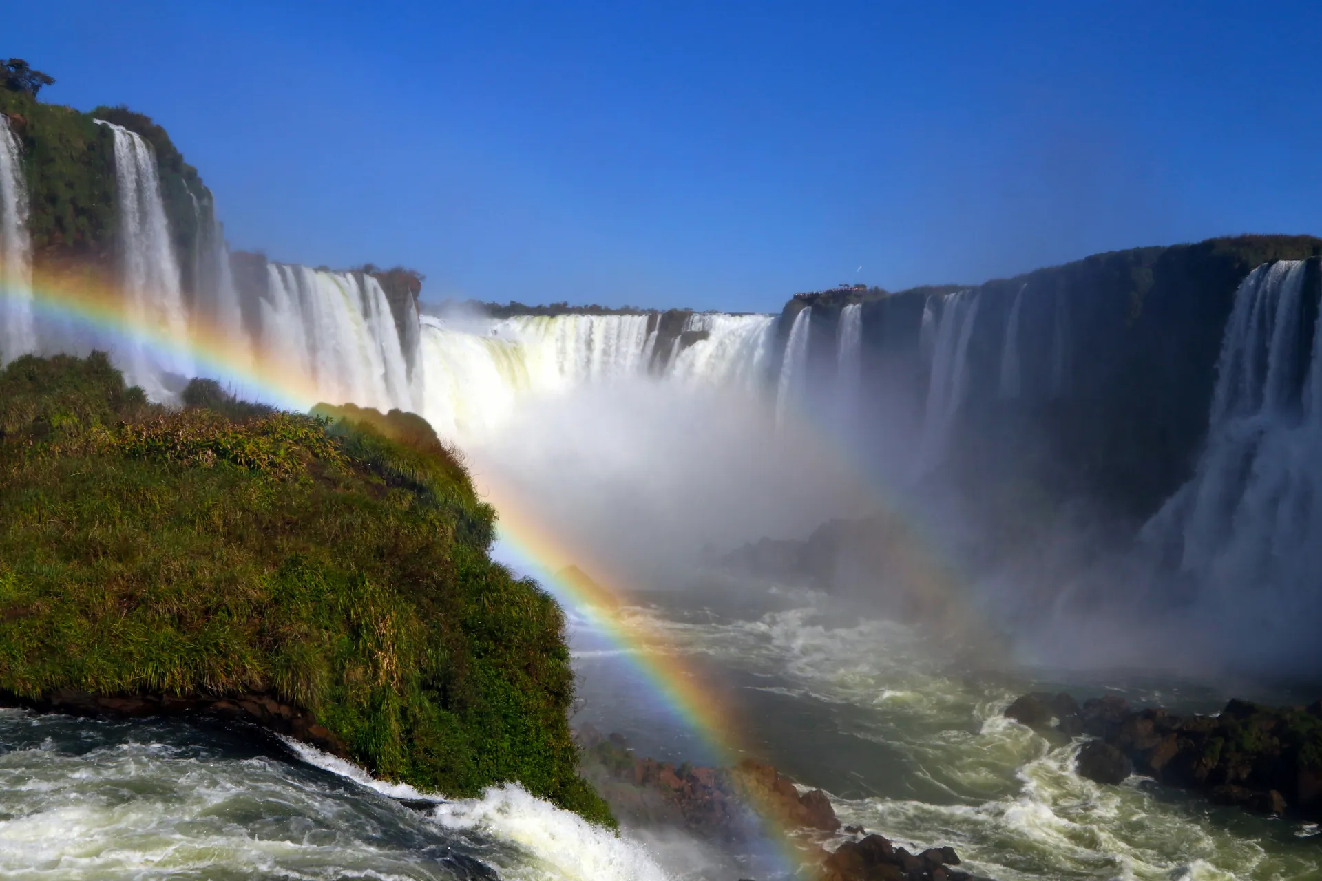 The Iguaçu Falls glowing in warm evening light with a rainbow in the mist