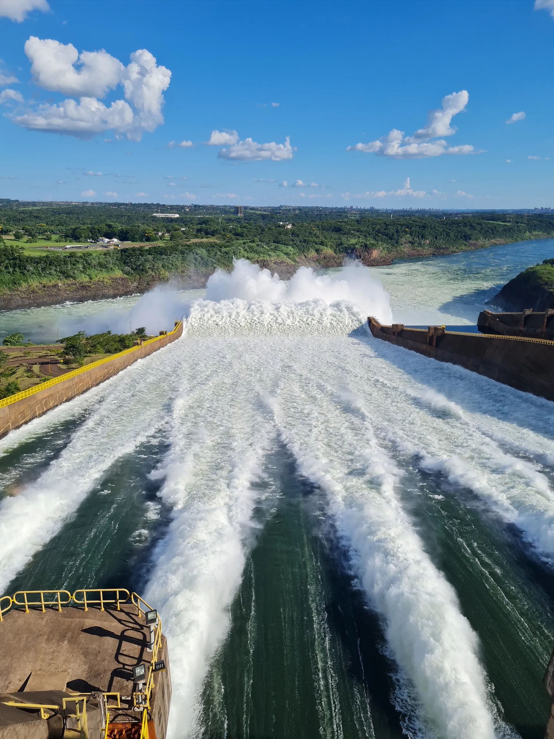 The vast Itaipu Dam lit up with coloured lights after dark, water rushing down the spillway