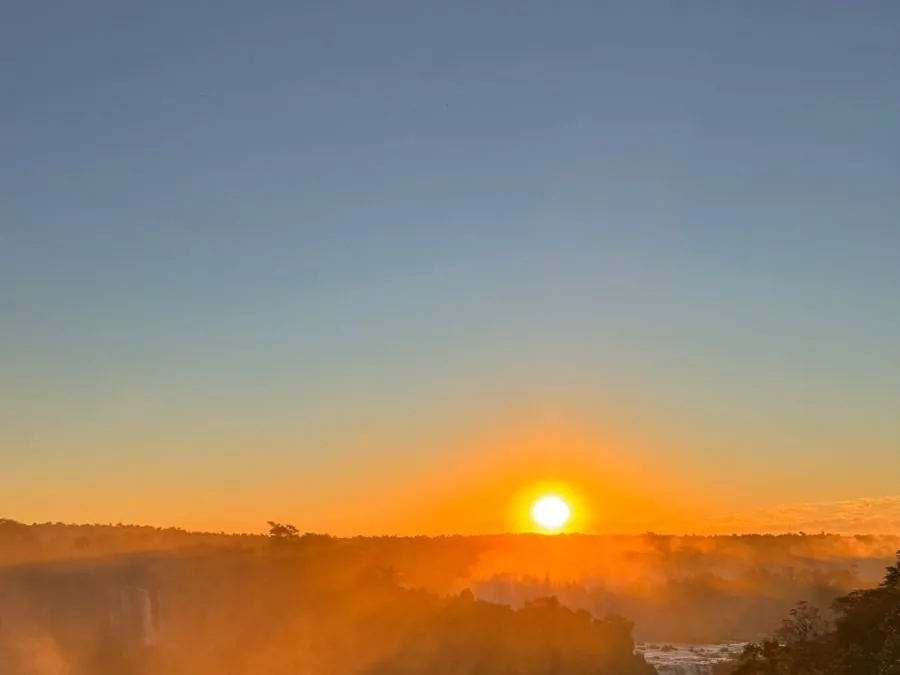 The sun setting over the Iguaçu gorge, mist glowing orange above the rainforest