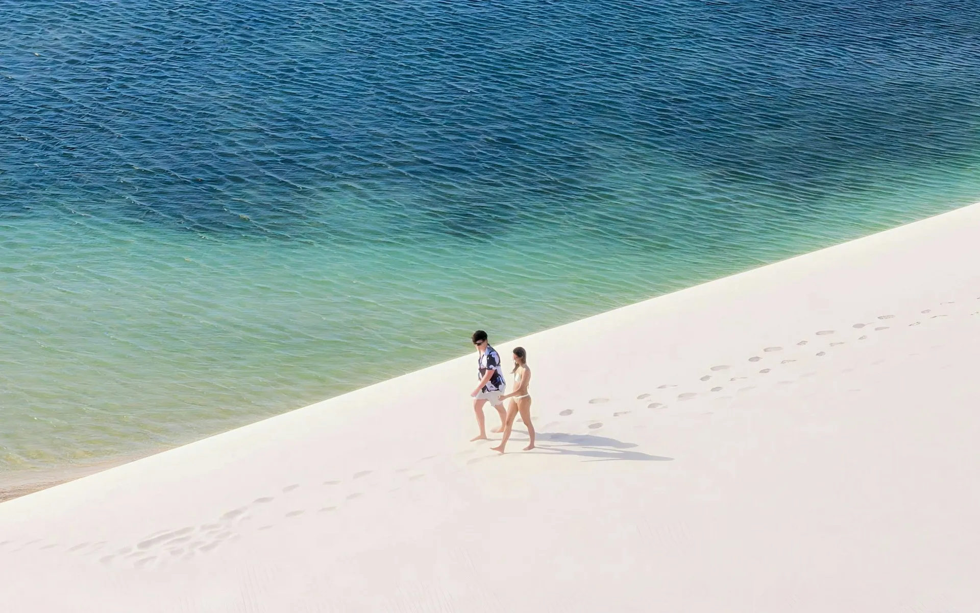 Trekkers crossing the dunes toward a remote oasis village in the Lençóis interior
