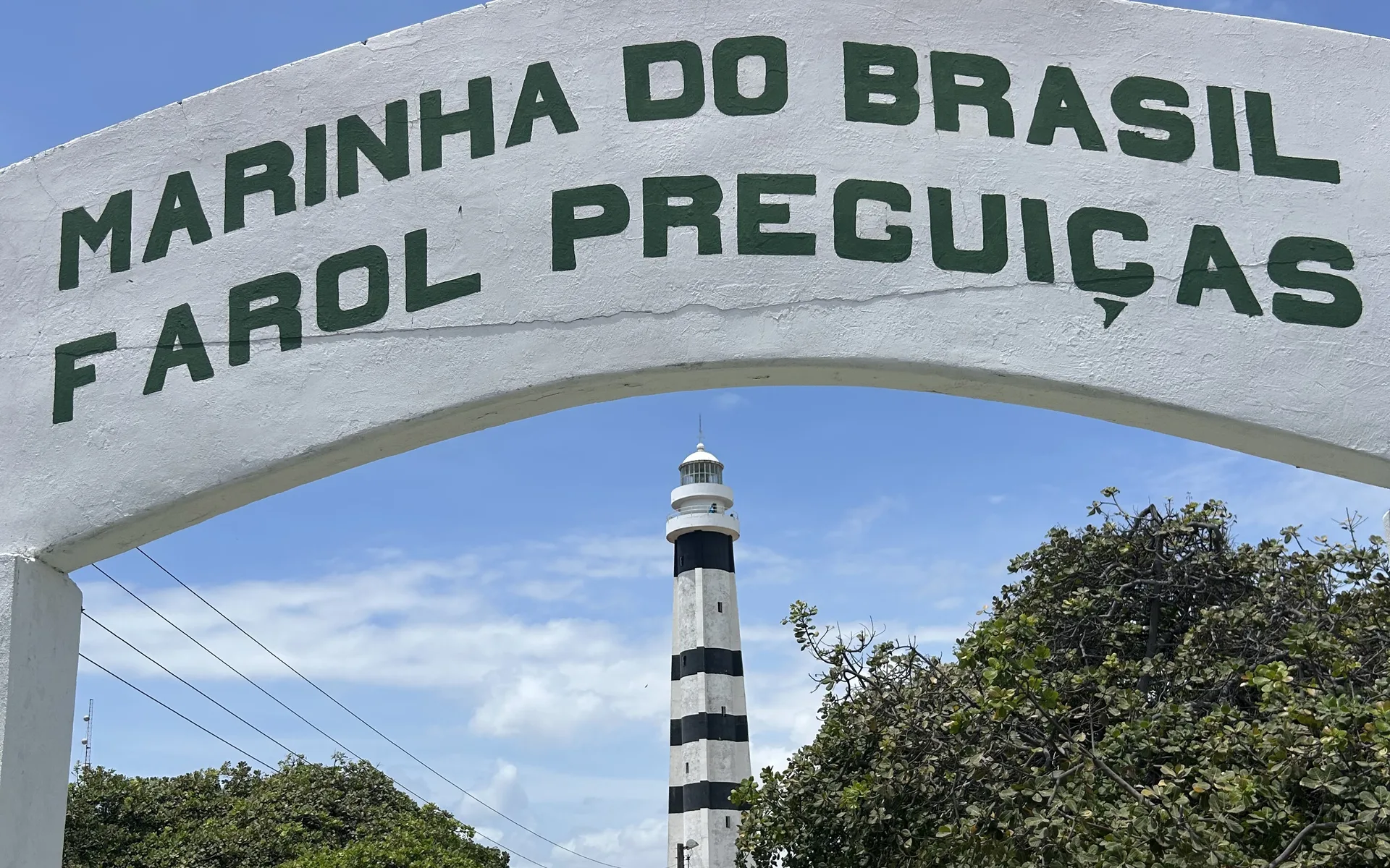 A boat on the Rio Preguiças passing the leaning lighthouse at Mandacaru