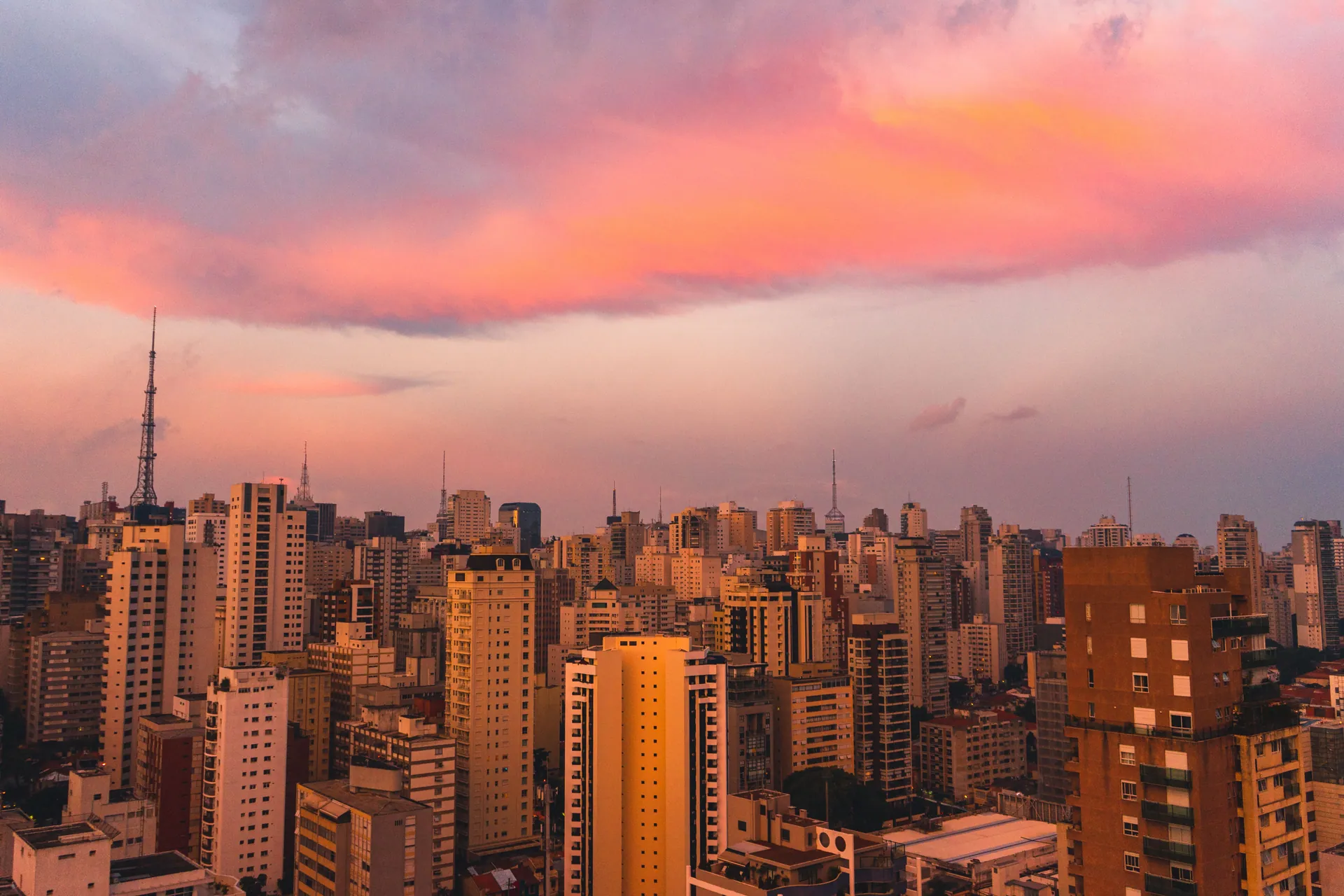 The São Paulo skyline stretching to the horizon under a pink sunset sky